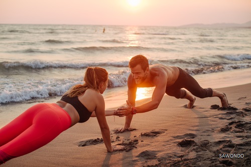 homme et femme sportifs faisant des pompes workout sur la plage avec l'entraînement au poids du corps - mon programme forme et bien être pour cet été